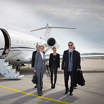Business professionals exiting a private jet on an airstrip.