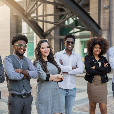 Four young professionals standing with arms crossed, smiling outdoors.